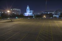 an empty parking lot and a tall building at night time in a big city city