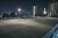 an empty parking lot and a tall building at night time in a big city city