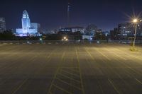 an empty parking lot and a tall building at night time in a big city city