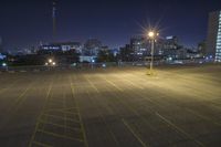 an empty parking lot and a tall building at night time in a big city city