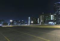 an empty parking lot and a tall building at night time in a big city city