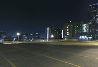 an empty parking lot and a tall building at night time in a big city city