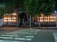 a street with several rows of lamps on either side of the road, two people crossing over a street