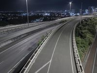 an urban highway at night with the city lights on and buildings lit up in the background