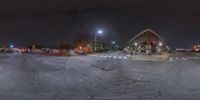 a stoplight that is above a road at night time and a man on skateboard in the foreground