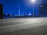 an empty parking lot with an urban skyline in the background at night time and two people standing nearby