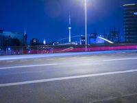 an empty parking lot with an urban skyline in the background at night time and two people standing nearby