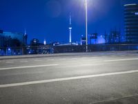 an empty parking lot with an urban skyline in the background at night time and two people standing nearby