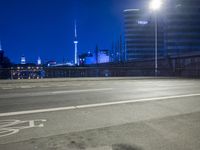 an empty parking lot with an urban skyline in the background at night time and two people standing nearby
