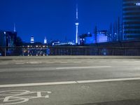 an empty parking lot with an urban skyline in the background at night time and two people standing nearby