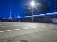 an empty parking lot with an urban skyline in the background at night time and two people standing nearby