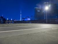 an empty parking lot with an urban skyline in the background at night time and two people standing nearby