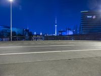 an empty parking lot with an urban skyline in the background at night time and two people standing nearby