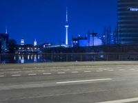 an empty parking lot with an urban skyline in the background at night time and two people standing nearby