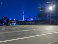 an empty parking lot with an urban skyline in the background at night time and two people standing nearby
