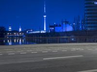 an empty parking lot with an urban skyline in the background at night time and two people standing nearby