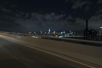 the view from a moving car on a freeway at night, of a city skyline