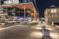 large open courtyard with steps to it, along side an office building at night at dusk