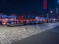 the lights in the area are on the brick floored area of the waterfront walkway