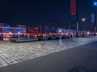 the lights in the area are on the brick floored area of the waterfront walkway