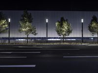 a large white building with trees on the street side at night time in front of it