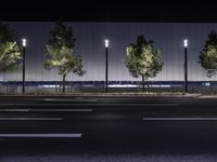 a large white building with trees on the street side at night time in front of it