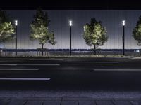 a large white building with trees on the street side at night time in front of it