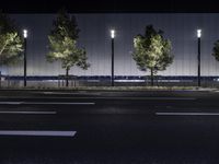 a large white building with trees on the street side at night time in front of it