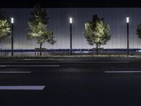 a large white building with trees on the street side at night time in front of it