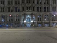 a building with several windows is lit up by red lights and a traffic light that is sitting on the side of the road