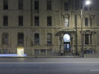 a building with several windows is lit up by red lights and a traffic light that is sitting on the side of the road
