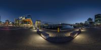 fish eye view of some buildings on a waterfront at night by water and lights on