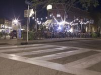 a crosswalk with lights in a city street at night with a traffic signal and people