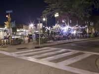 a crosswalk with lights in a city street at night with a traffic signal and people
