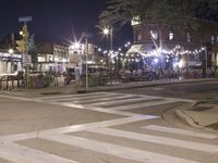 a crosswalk with lights in a city street at night with a traffic signal and people