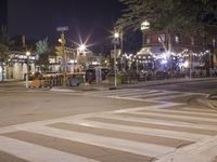 a crosswalk with lights in a city street at night with a traffic signal and people