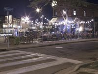 a crosswalk with lights in a city street at night with a traffic signal and people
