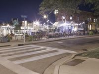 a crosswalk with lights in a city street at night with a traffic signal and people