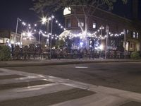 a crosswalk with lights in a city street at night with a traffic signal and people