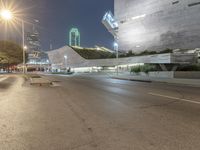 empty street with city buildings on both sides of the road at night, with street lamps