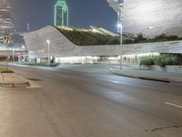 empty street with city buildings on both sides of the road at night, with street lamps