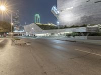 empty street with city buildings on both sides of the road at night, with street lamps