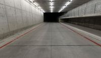 a tunnel with the floor almost covered by concrete slabs and red striped pavement below a large cement structure