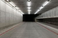 a tunnel with the floor almost covered by concrete slabs and red striped pavement below a large cement structure