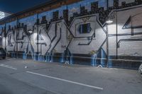 a car is parked next to the wall with graffiti on it at night in a parking garage