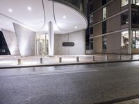 a building is shown at night next to the street corner with an empty street and an empty street lined by buildings