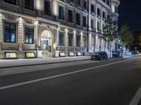 some cars are on the street in the evening light at night with lights that shine brightly against the building