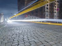 the sidewalk is brick with a bridge on top it in the city at night,