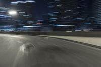 a motion blur photograph of a highway in a city at night with a car going along the right bank