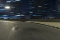 a motion blur photograph of a highway in a city at night with a car going along the right bank